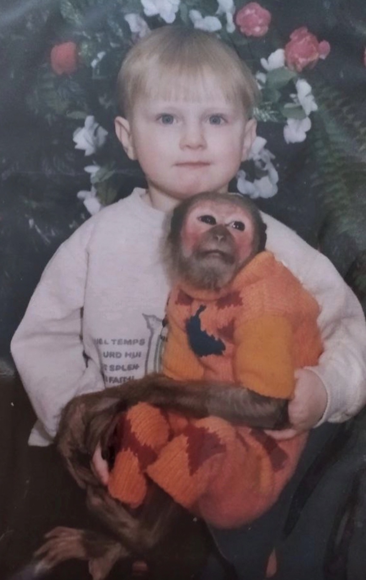 Stanislav as a child holding a monkey wearing an orange sweater